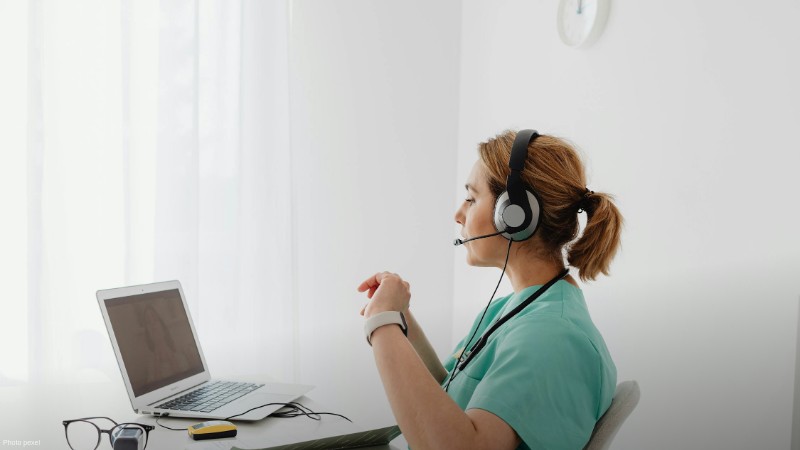 A female doctor using a laptop for an online consultation, wearing a headset in a bright office., tags: executive - pexel
