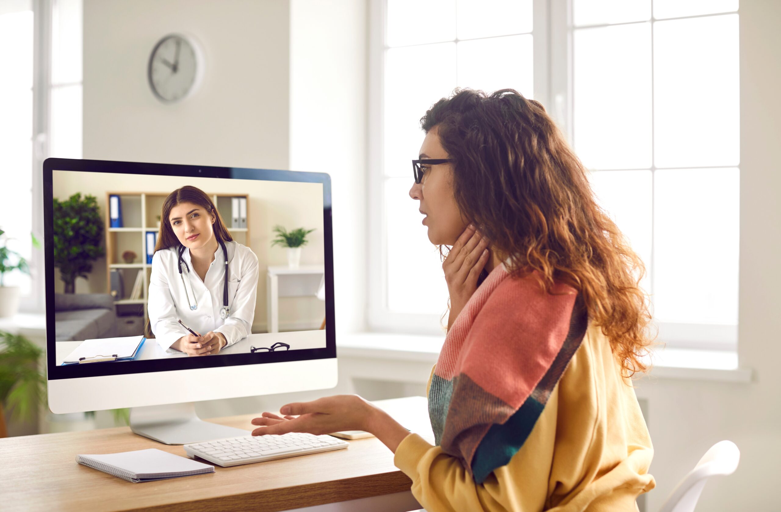 Female patient with a sore throat having online medical consultation via video call on computer.